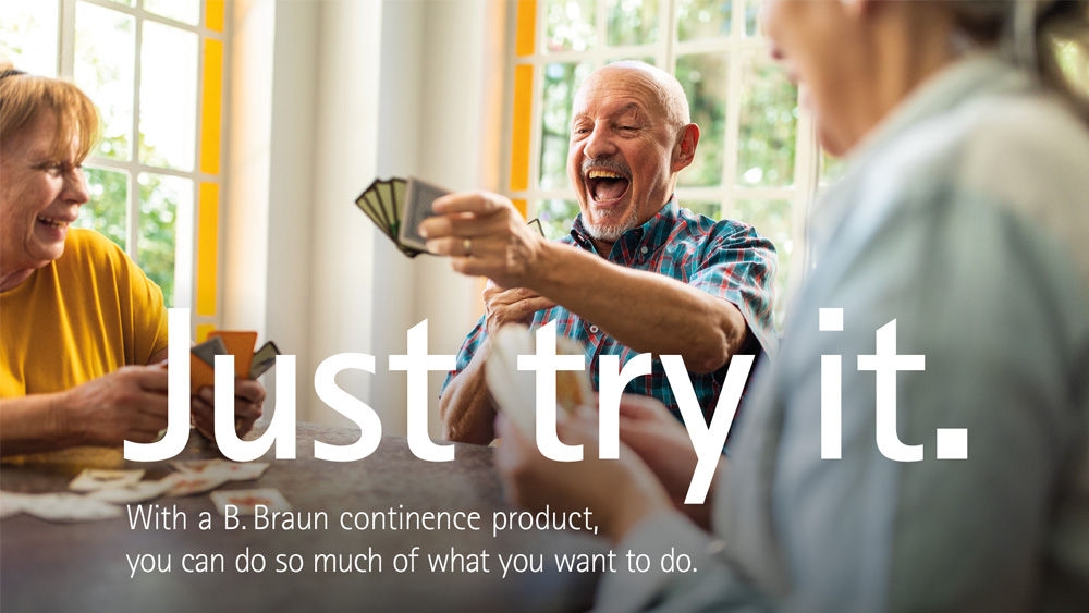 Three seniors sitting at a table playing cards, with one person holding a fan of cards and another person dealing. The scene is set in a bright room with large windows in the background. The text on the image reads: "Just try it. With a B. Braun ostomy continence product, you can do so much of what you want to."