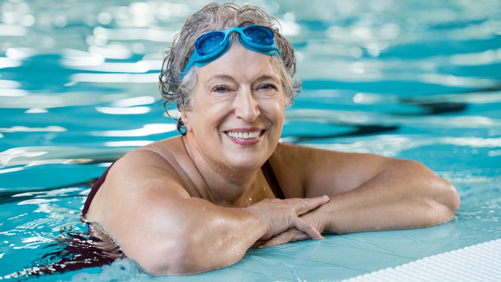 woman in swimming pool wearing swim googles on her forehead