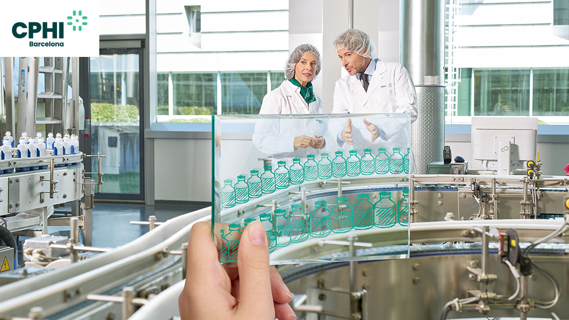 Two production workers in lab coats are discussing