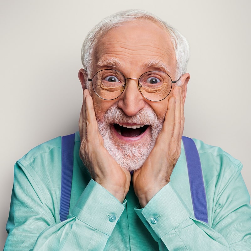 grandpa with glasses and beard who looks surprised and puts both hands to his face